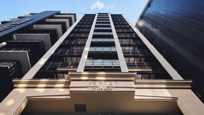 Un hôtel de grande hauteur doté d’une architecture moderne, caractérisé par une entrée imposante et de nombreux balcons.