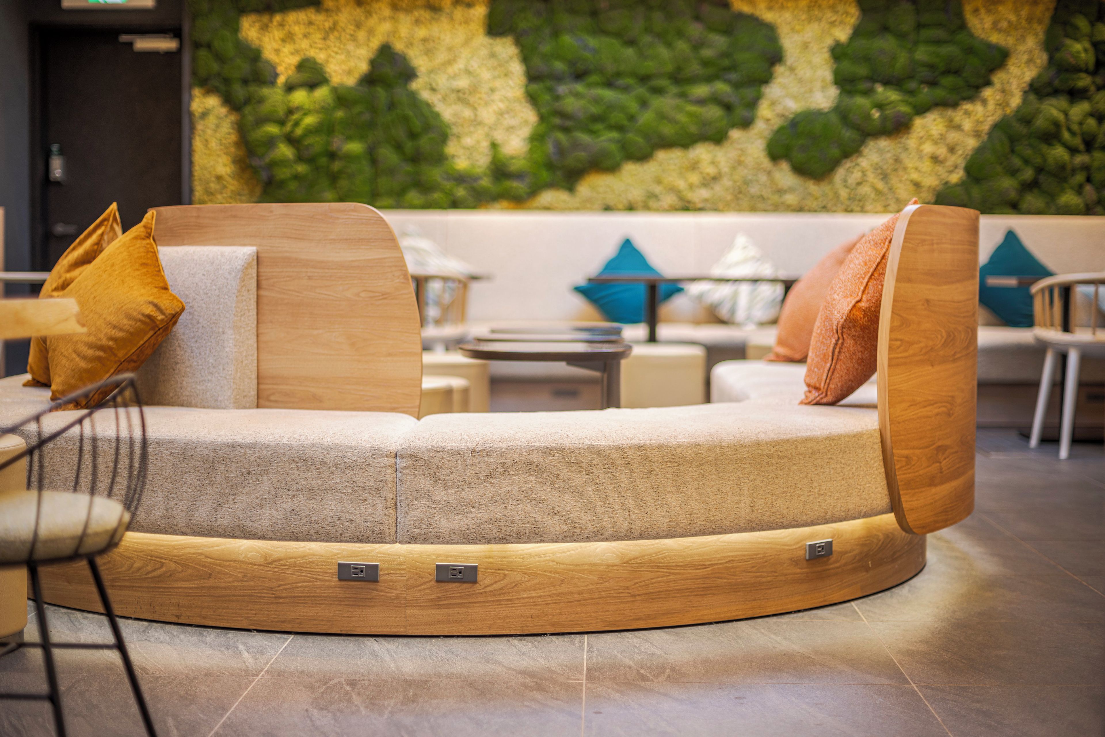 A round seating area with a sofa and armchairs, a small table, and a wall with a green leafy pattern.
