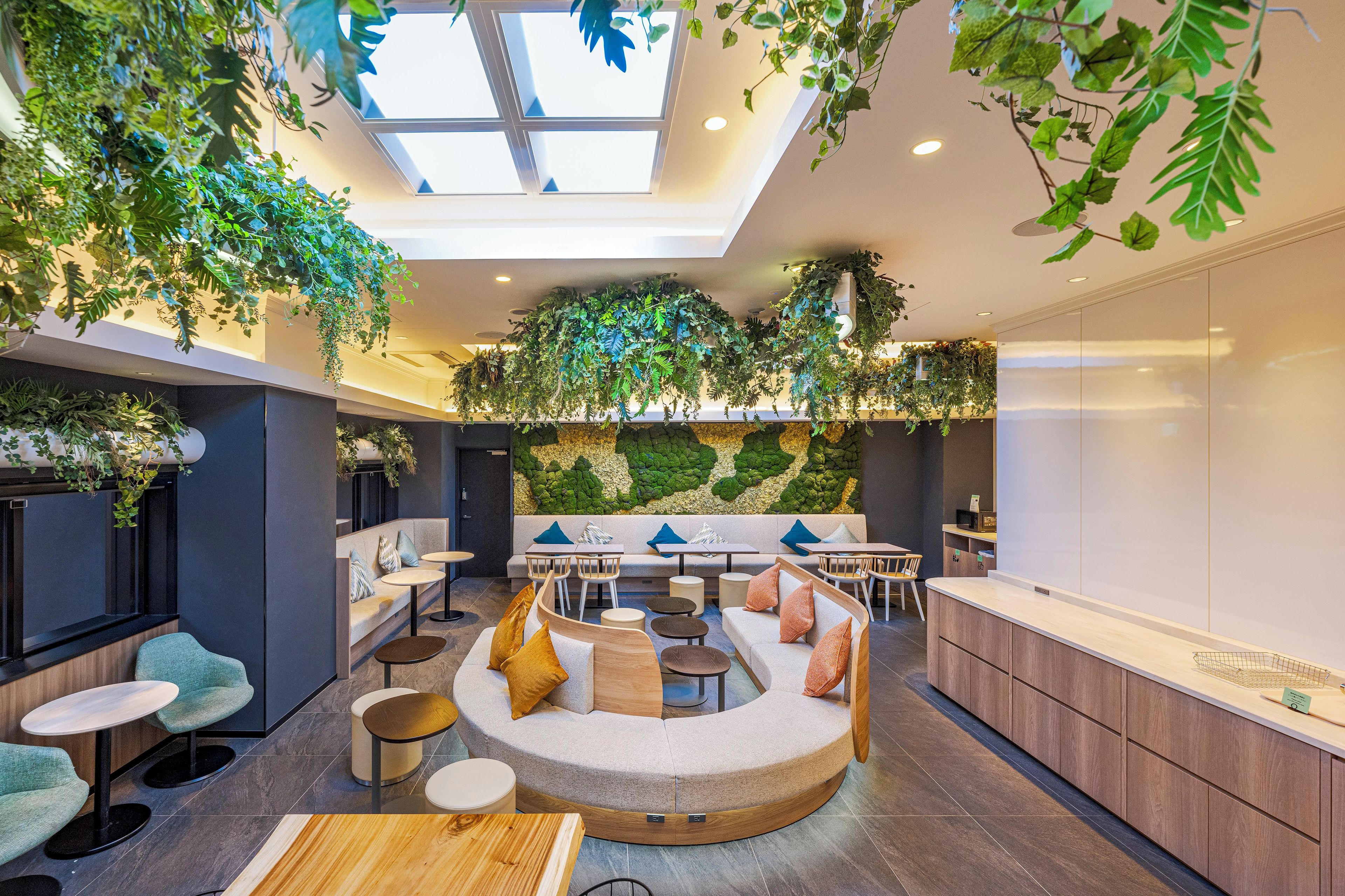 Ein modernes Interieur mit Oberlicht, Sitzbereichen und einer grünen Wand.