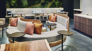 Un espace détente moderne avec un canapé incurvé, des tables rondes et des chaises en bois.