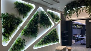 Un intérieur moderne agrémenté de jardins verticaux sur les murs, d’un espace détente avec des bancs en pierre et d’une vue sur la salle à manger.