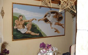 A painting of two muscular figures in dynamic poses, a decorative star-shaped light fixture, and a vase with purple flowers.