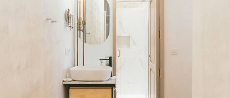 Un baño moderno con un lavamanos grande, un espejo y un perchero para toallas.
