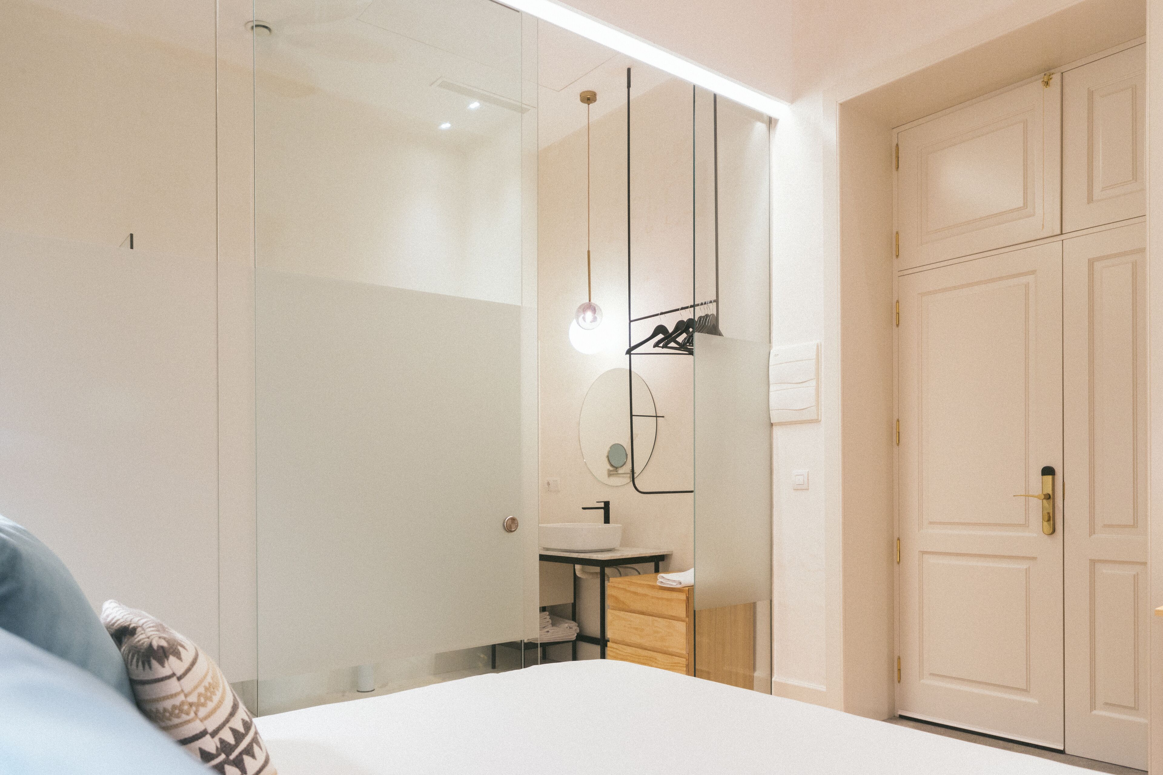 Ein modernes Schlafzimmer mit einem großen Bett, einem Nachttisch, einem Spiegel und einem Kleiderschrank.