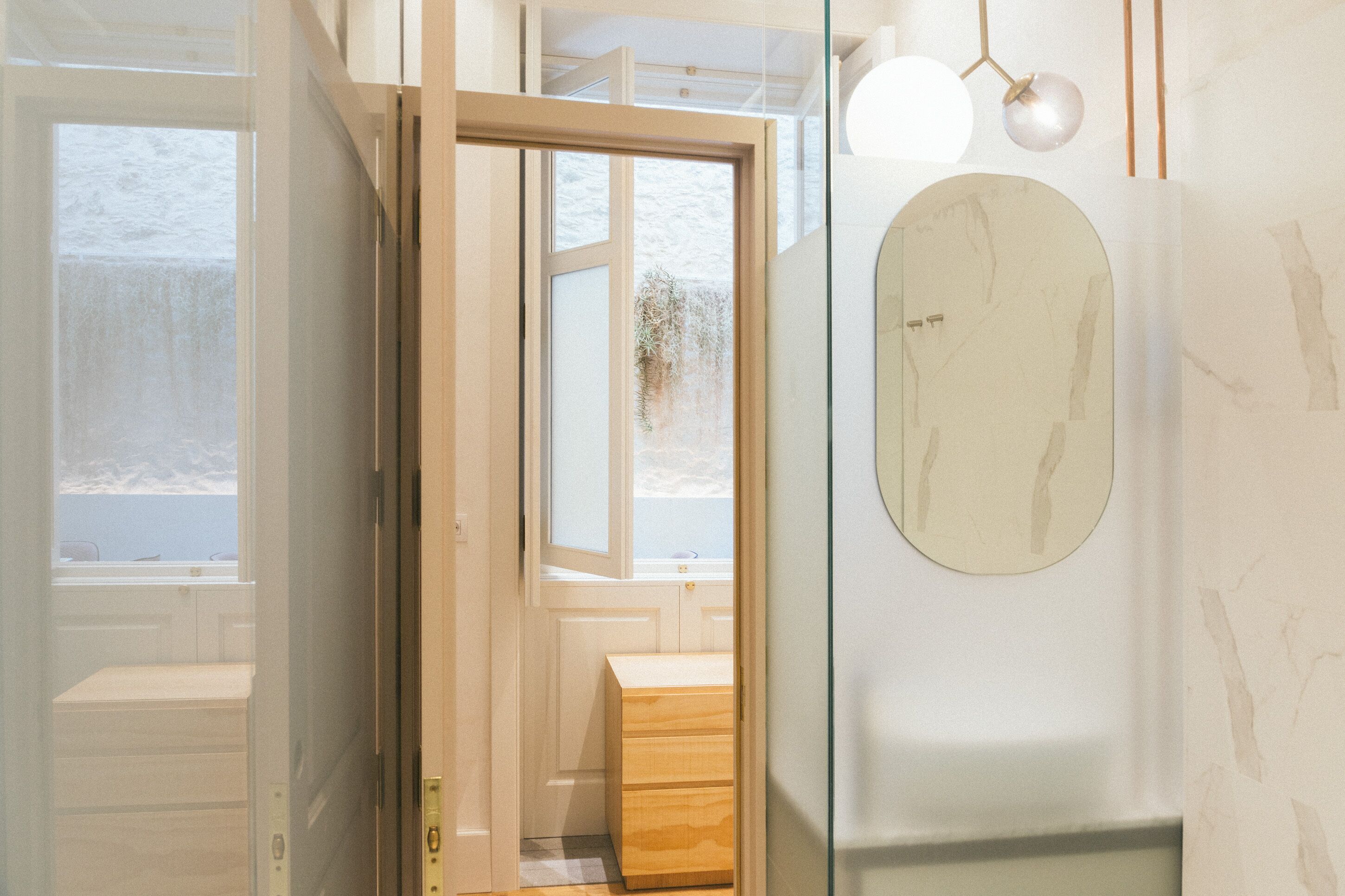 Une salle de bain moderne avec une douche à l’italienne en verre, un meuble-lavabo en bois et un grand miroir.