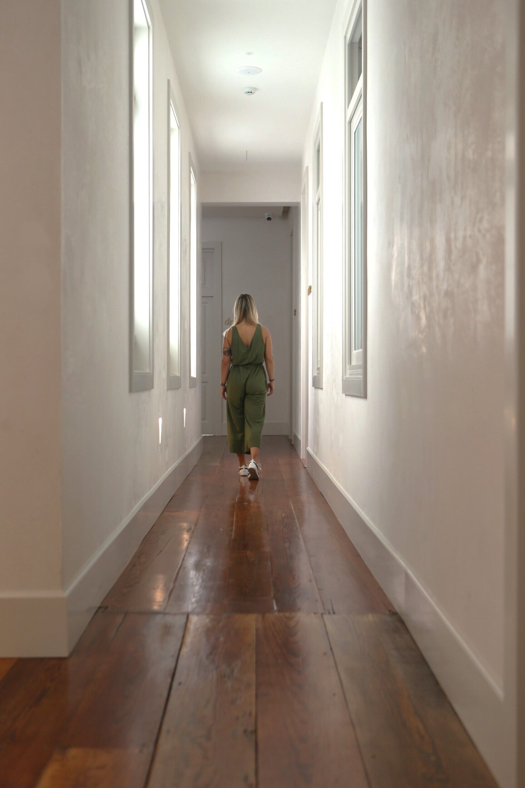 A hallway with wooden flooring and white walls.