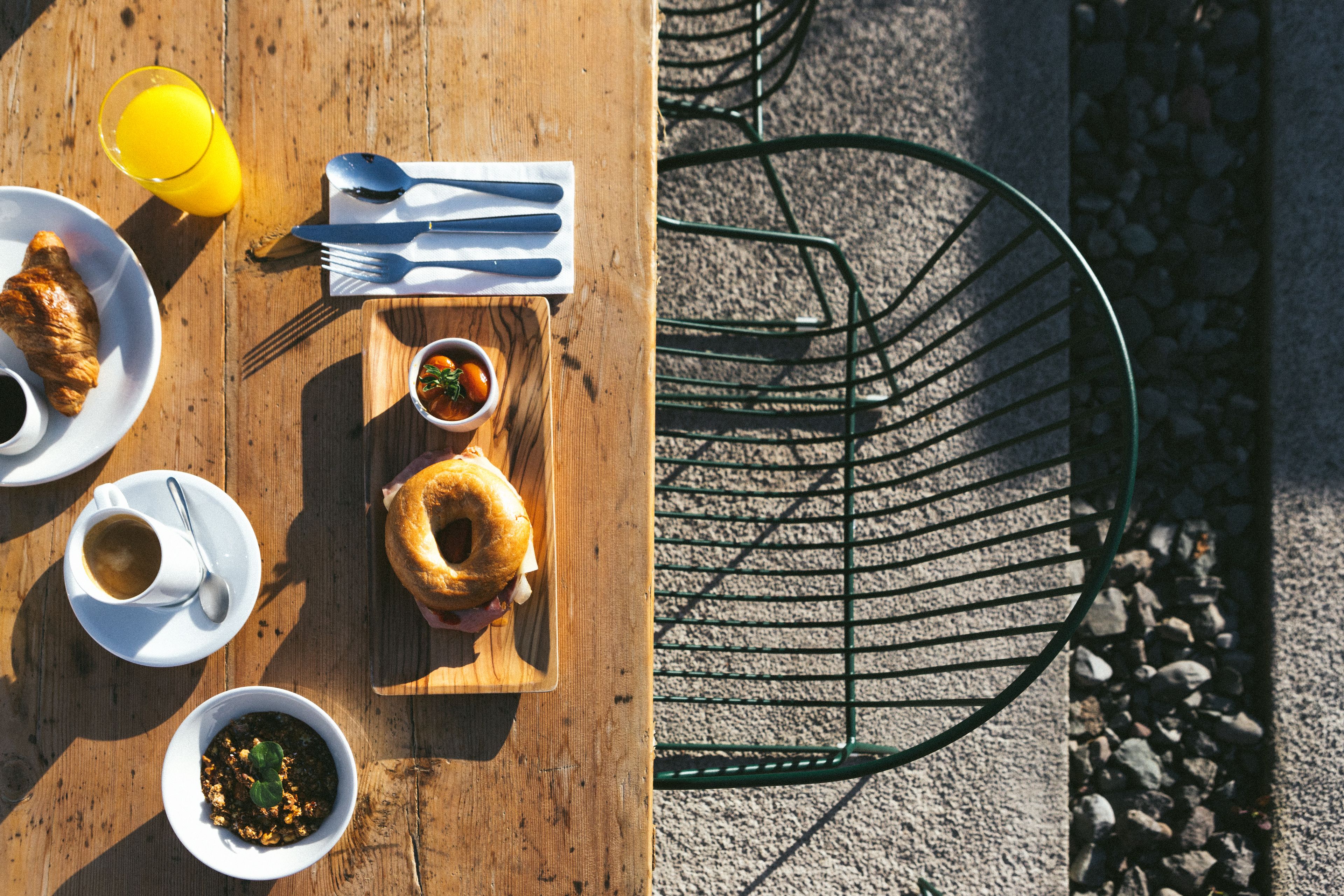 Un tavolo di legno con prodotti per la colazione, tra cui croissant, una ciotola di zuppa e una tazza di caffè.