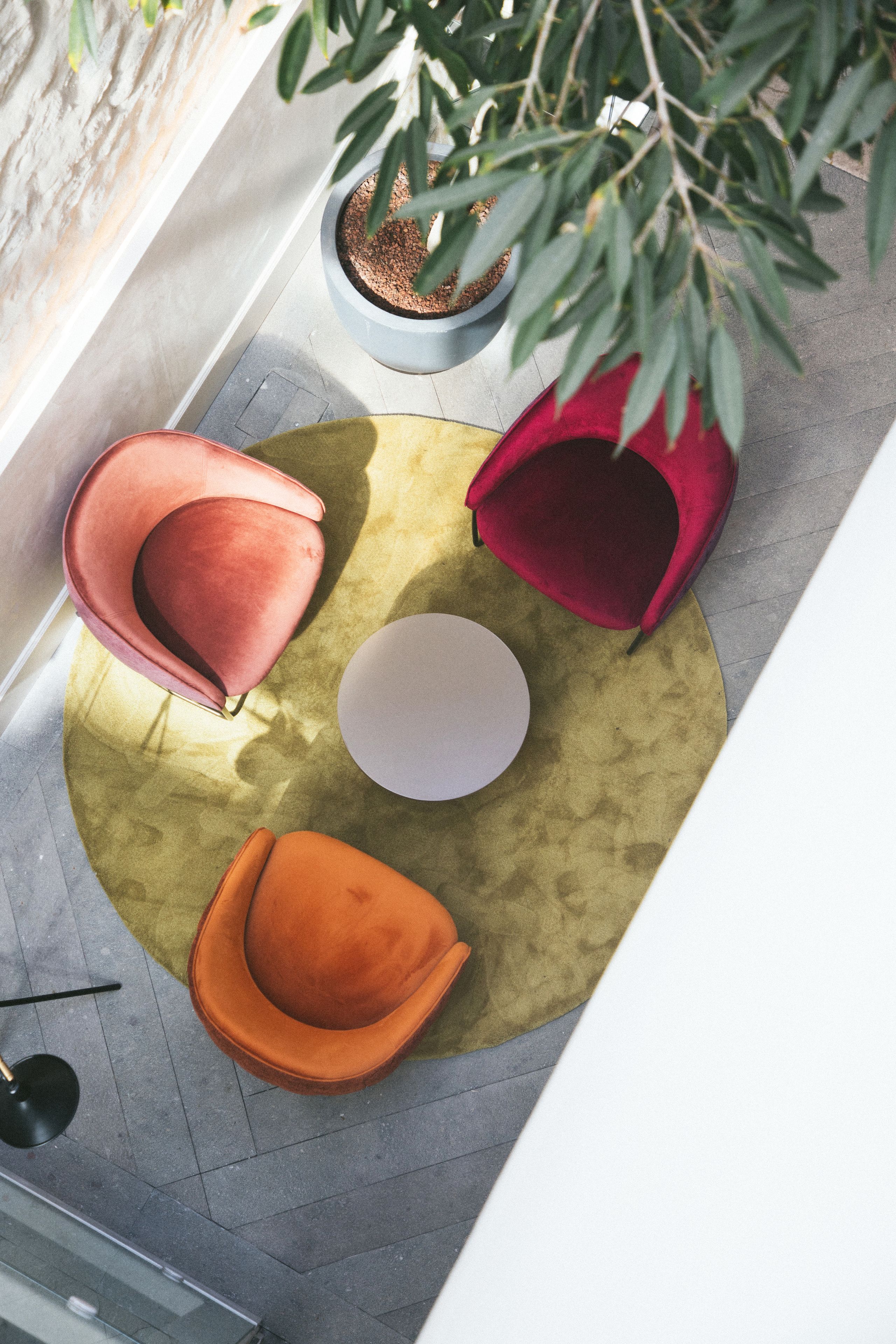 A top-down view of a room with two red chairs, a white table, and a potted plant.