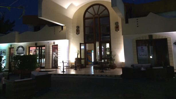 Un edificio con un gran acceso arqueado, zona de estar al aire libre y un letrero para un restaurante.