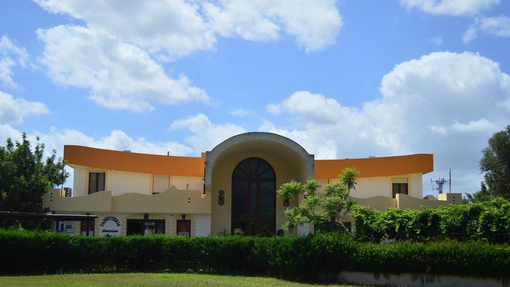 A building with a central arched entrance, a flat roof, and a sign indicating it is a restaurant.