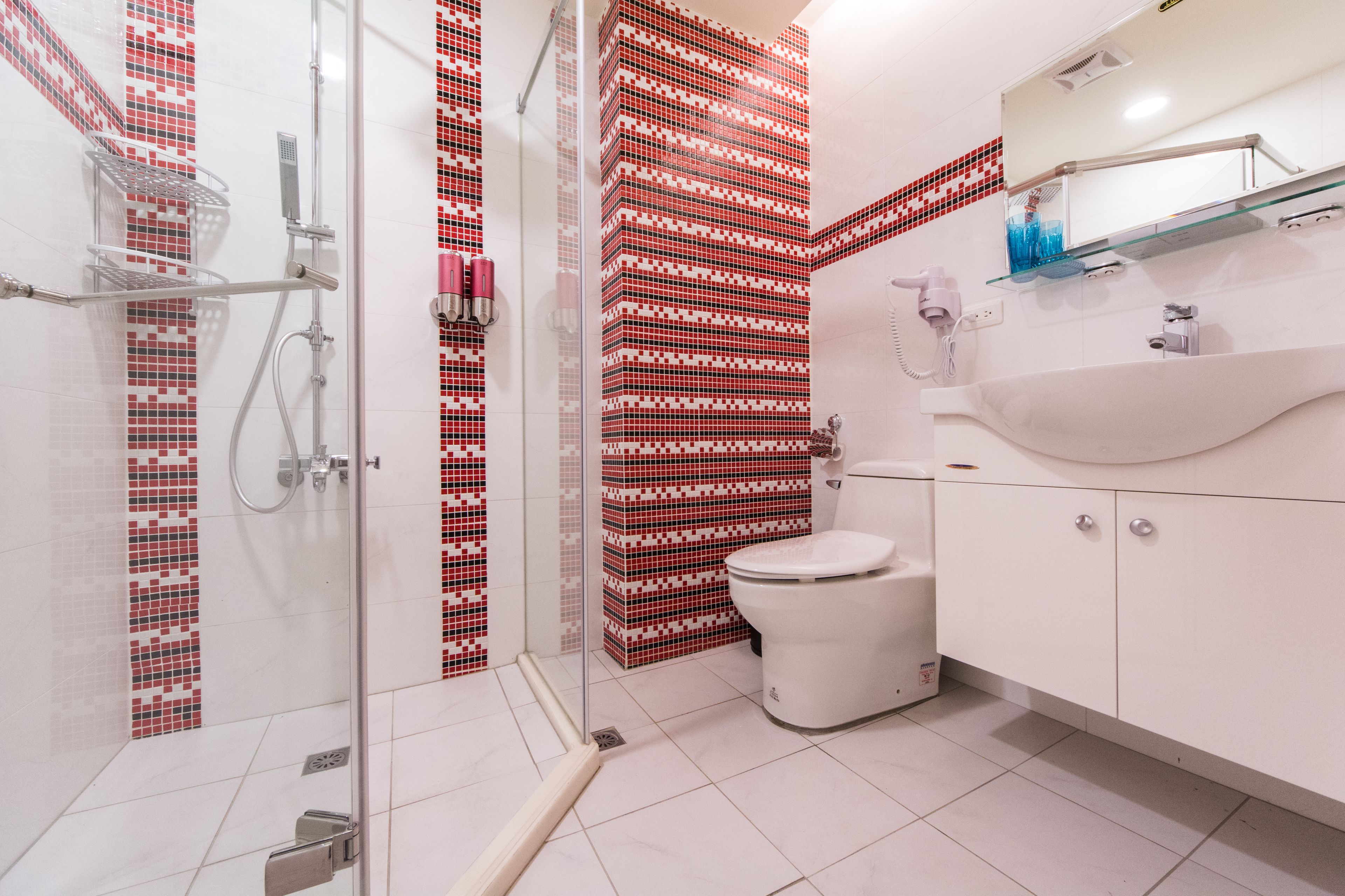A modern bathroom with a glass shower enclosure, a white toilet, and a sink with a mirror above it.