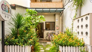 Un estrecho callejón con valla de madera, una bicicleta y plantas en macetas.