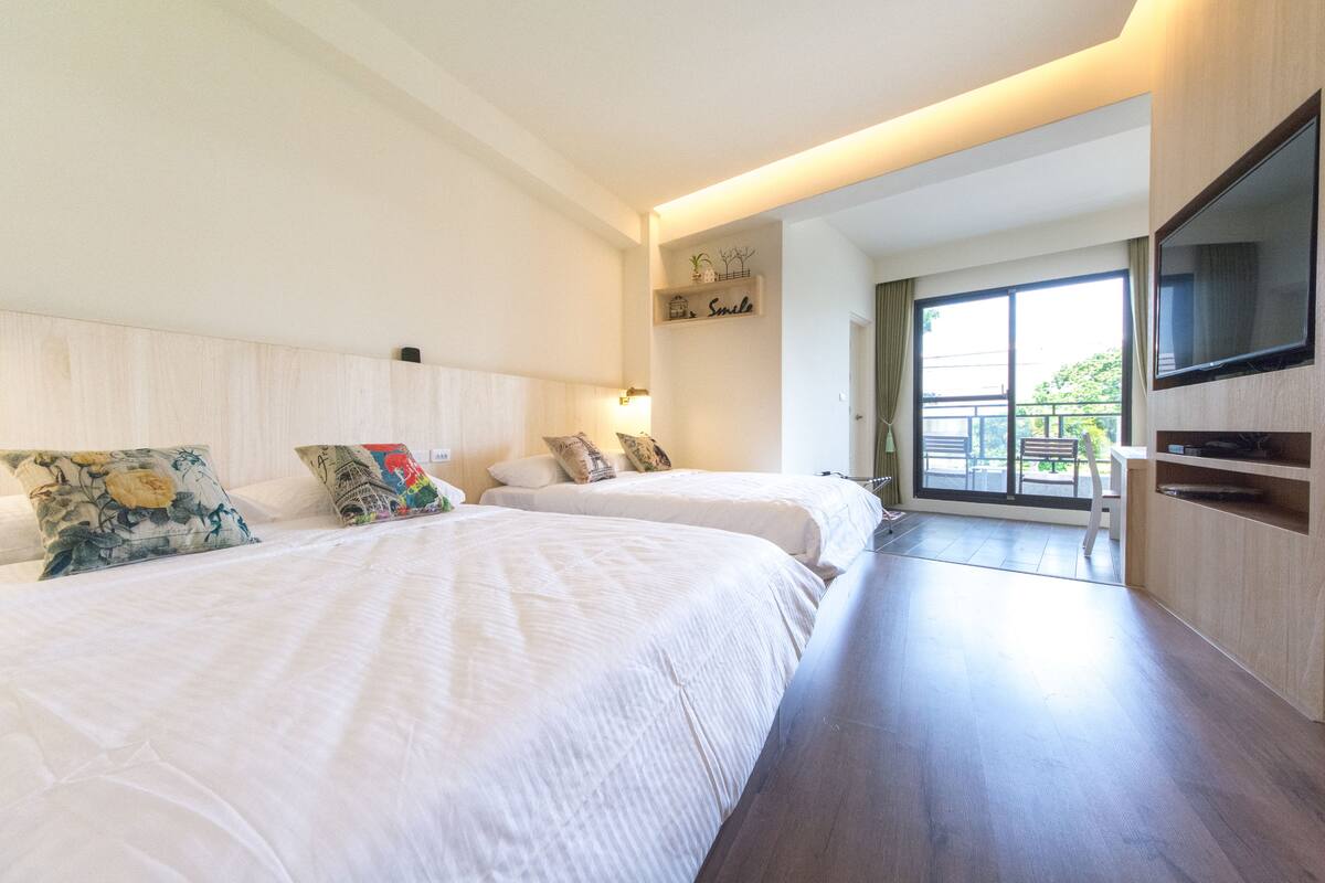 Una habitación de hotel moderna con dos camas, un televisor y un balcón con vistas.