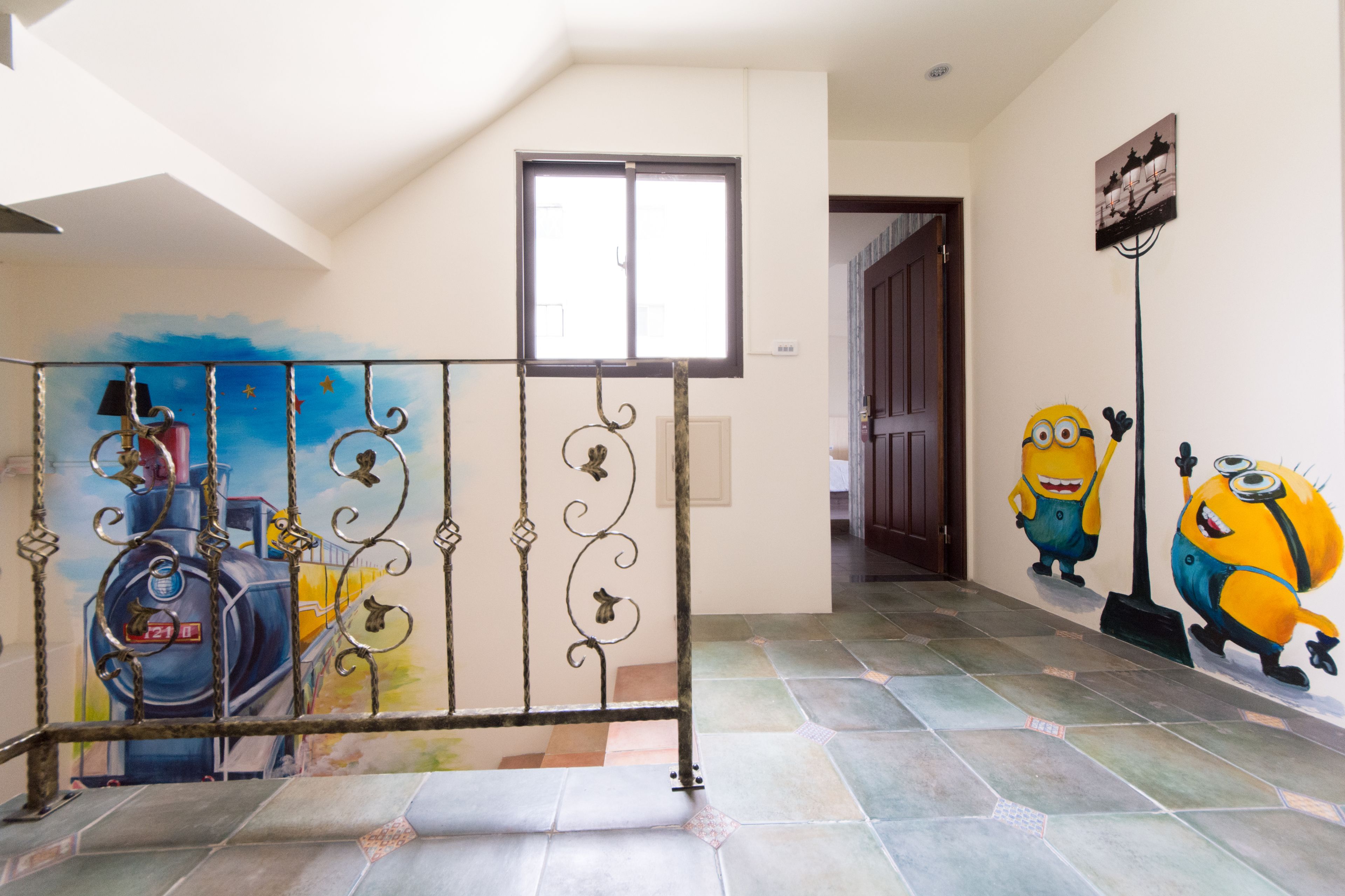 A staircase with a metal railing, a window, and a wall with a Minion mural.