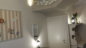 Un comedor con mesa y sillas de madera, una lámpara colgante y una estantería con objetos decorativos.