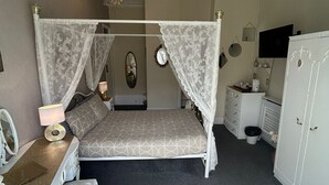 A bedroom with a four-poster bed, a desk with a chair, a dresser, and a wardrobe. - The little emily - Room only (Great Yarmouth)