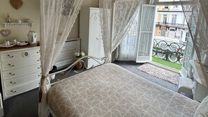A bedroom with a canopy bed, a dresser, and a view of the street outside. - The little emily - Room only (Great Yarmouth)