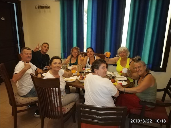A group of people dining at a table with a variety of dishes and drinks.