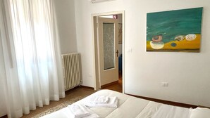 A hotel room with a bed, a painting on the wall, and a radiator. - Ca' Giulia (Venice)