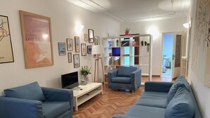 A living room with blue sofas, a TV, and a bookshelf. - Ca' Giulia (Venice)