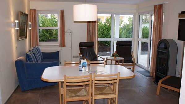 A dining area with a table and chairs, a sofa, a television, and a fireplace.
