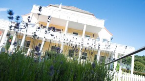 Un bâtiment blanc doté de nombreux balcons, avec une clôture blanche en premier plan.