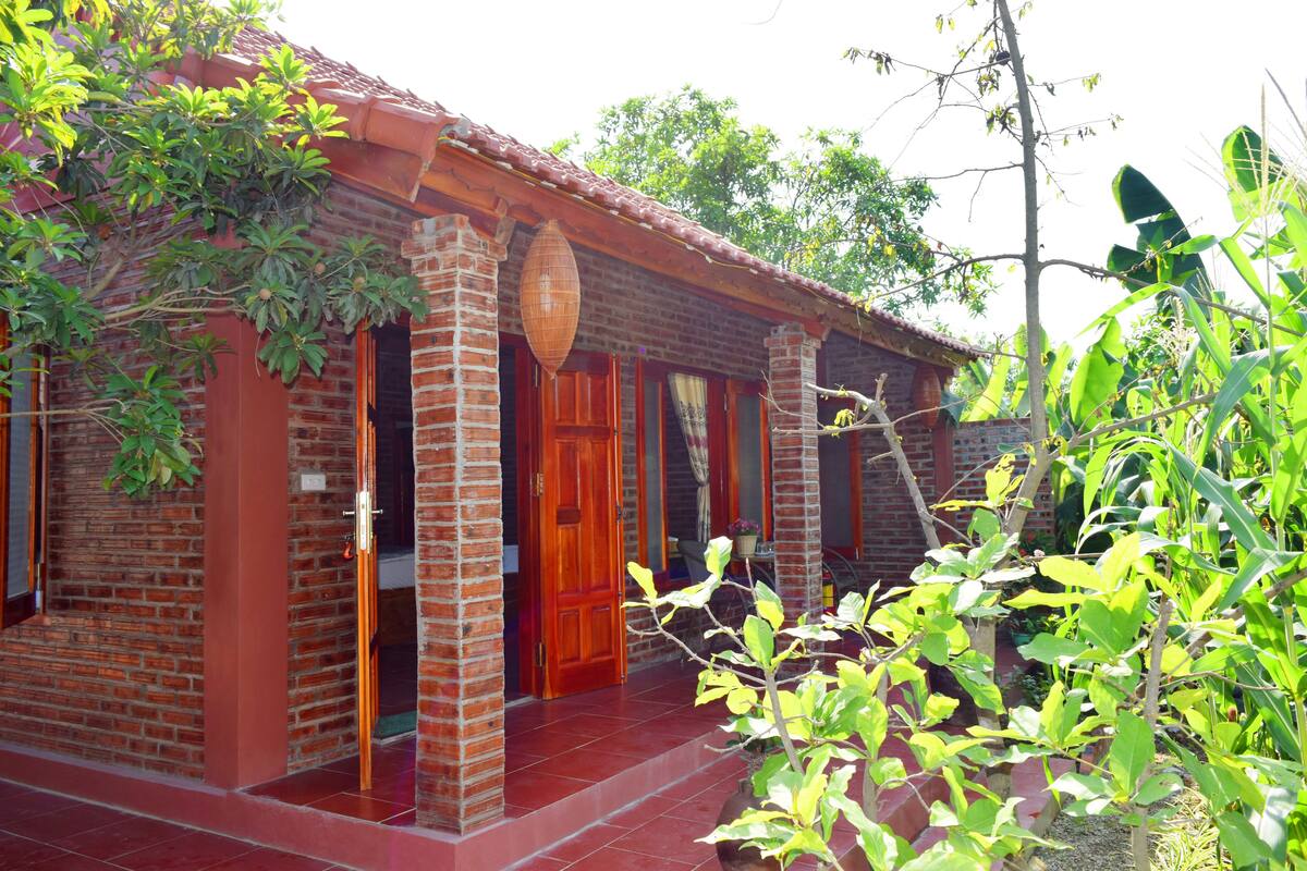 A brick house with a tiled porch, a wooden door, and a hanging lantern.