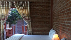 Una habitación con cama, una mesa, sillas y una pared de ladrillo.