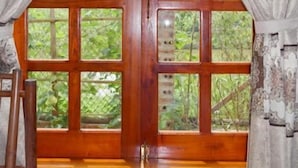 Una habitación con un ventanal grande de madera enmarcado en madera oscura, flanqueado por cortinas estampadas.