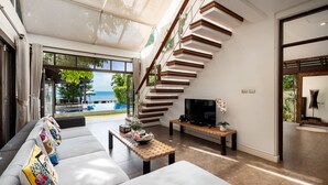 Una sala de estar moderna con un sofá, una mesa de centro, un televisor y una escalera.