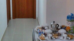 A hallway with a wooden door and a breakfast table with various food items and a coffee maker. - Bed and Breakfast Ocurniciell (Naples)