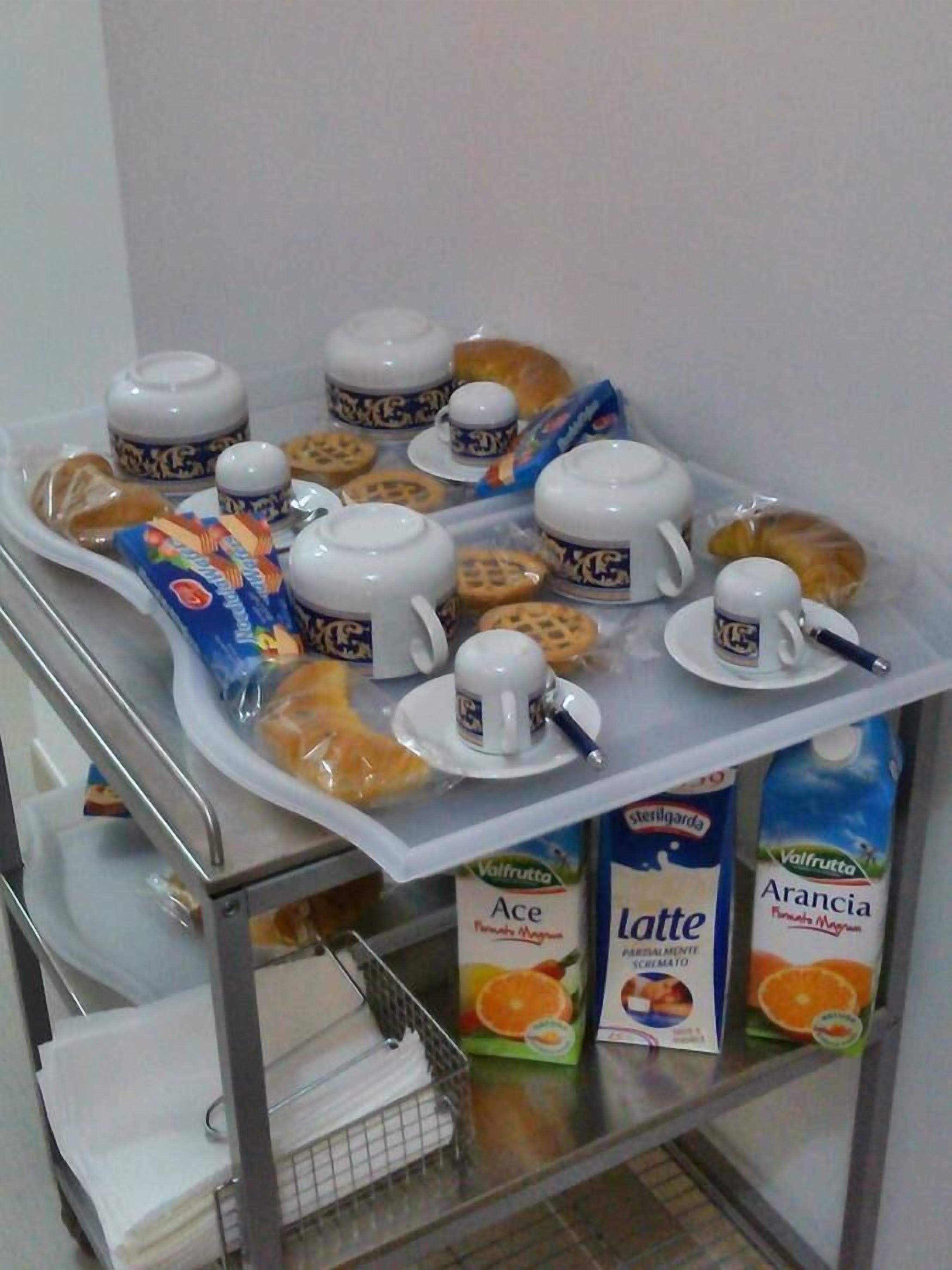 A breakfast trolley with coffee cups, teapots, pastries, and juice cartons.