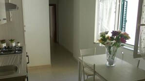 A kitchen with a stove, a dining table with chairs, and a vase with flowers on the table. - Bed and Breakfast Ocurniciell (Naples)