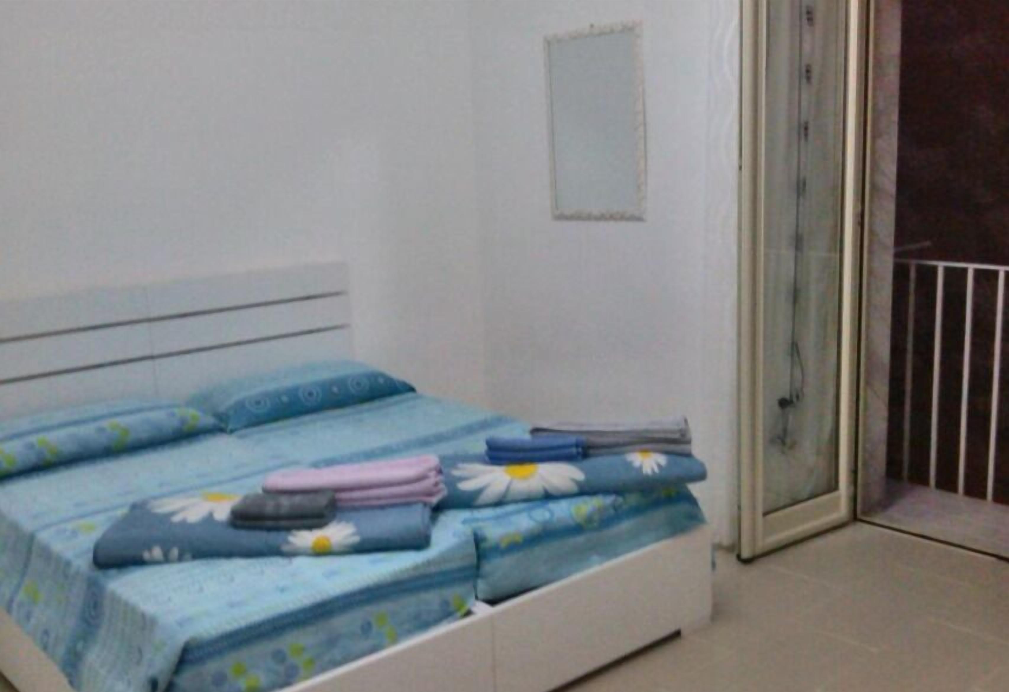 A bedroom with a bed, a small window, and a sliding glass door leading to a balcony.