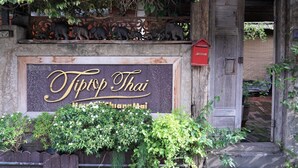 Letrero de 'Tiptop Thai' con una escultura decorativa de elefante encima.