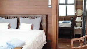 Un dormitorio con paneles de madera, una cama, una mesita de noche y una silla.