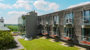 Un bâtiment moderne doté de nombreux balcons, d’une façade en verre et d’une pelouse bien entretenue.