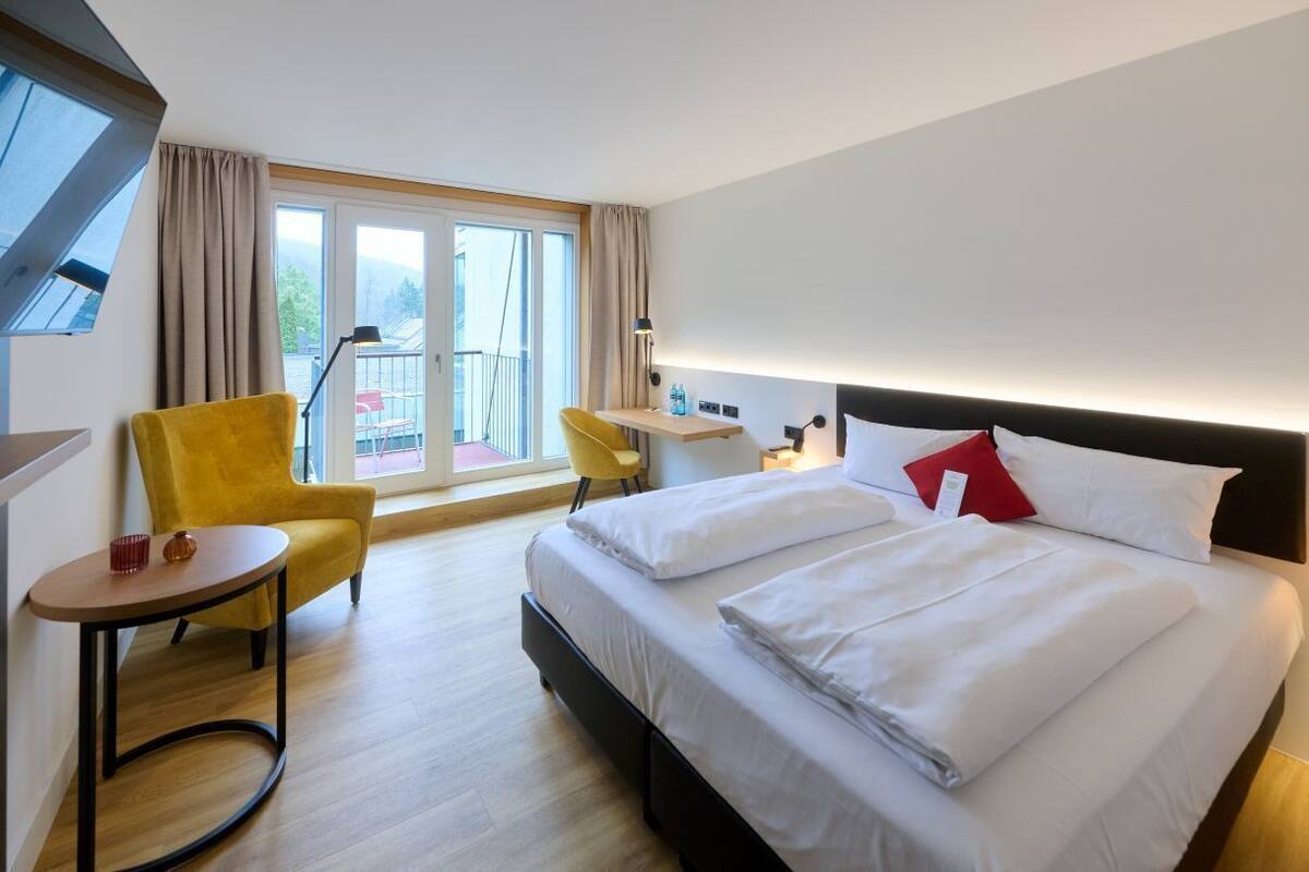 Een hotelkamer met een bed, een bureau, een stoel en een balkon met uitzicht.