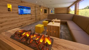 Un intérieur moderne avec une cheminée, des murs en bois et un coin salon agrémenté d’une grande fenêtre.