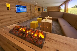 Un interior moderno con chimenea, paredes de madera y una zona de estar con un gran ventanal.