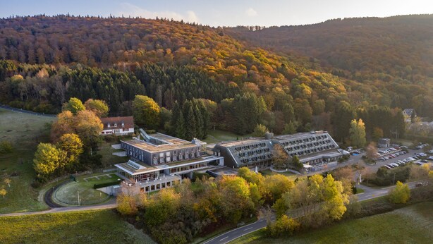 Vue aérienne d’un complexe de bâtiments modernes entouré d’un feuillage automnal.