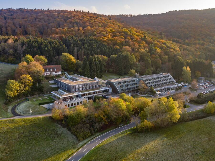 An aerial view of a modern building complex surrounded by autumn foliage.