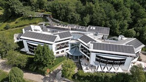 A modern building with multiple levels, solar panels, and a central courtyard.