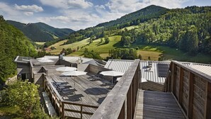 A rooftop terrace with wooden decking, solar panels, and outdoor seating.