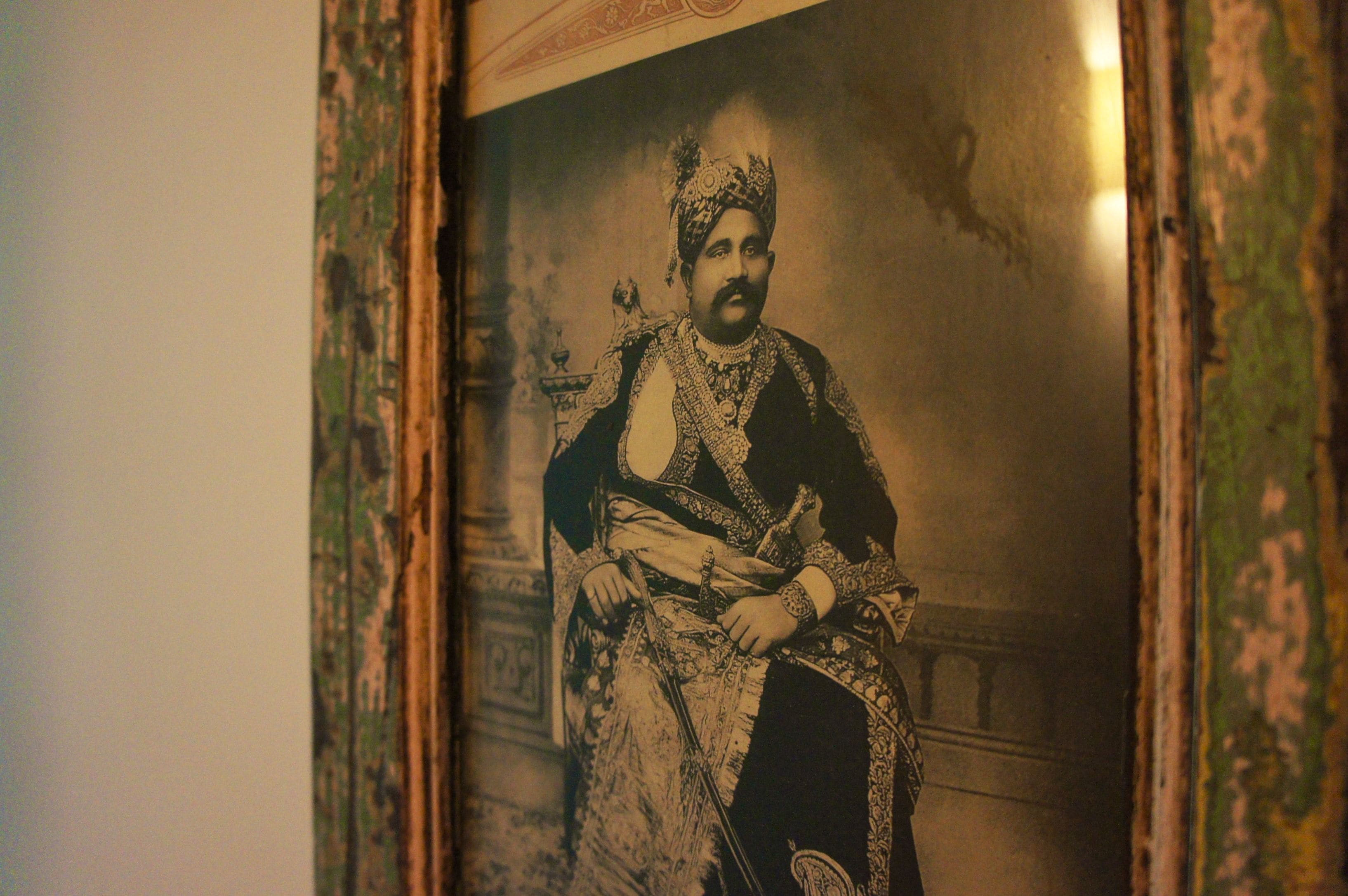 A framed portrait of a person in traditional attire, with ornate patterns on the frame.