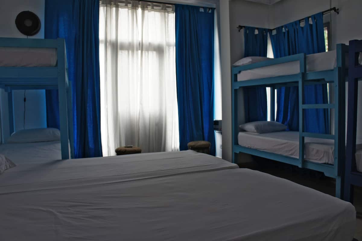 Ein Zimmer mit Etagenbetten, einem großen Bett und einem Fenster mit Vorhängen.