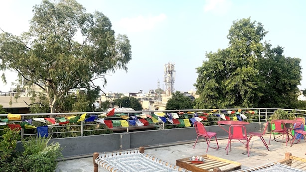 A rooftop terrace with a hammock, red chairs, and prayer flags. - Bed & Chai Guest House (New Delhi)