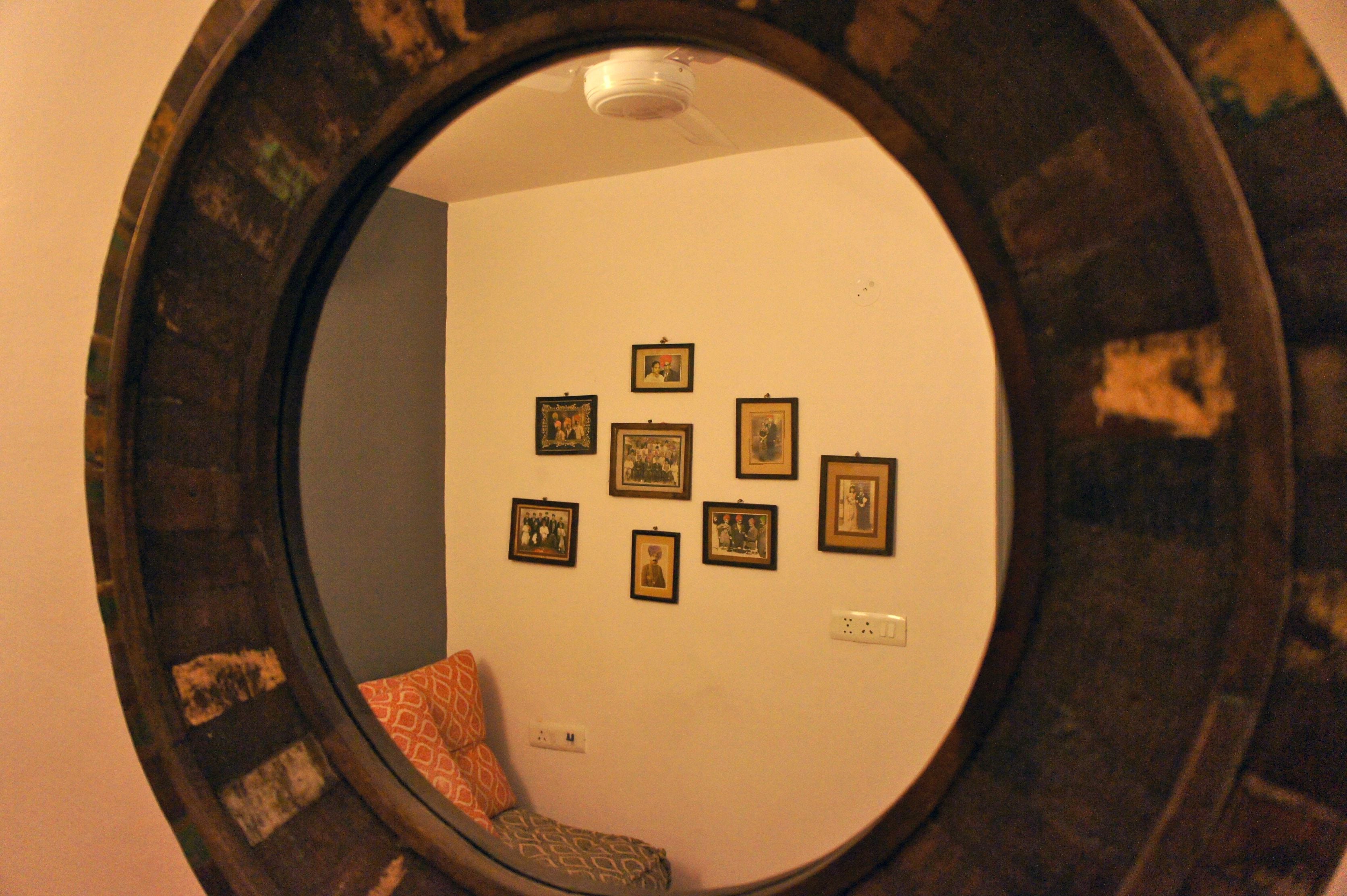 Una habitación con un espejo redondo que refleja una pared con varias fotografías enmarcadas.