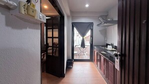 A narrow hallway leading to a dining area with a view, a kitchen with dark cabinets, and a door with a sign. - TJR Boutique House (Chiang Mai)