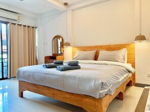 Un dormitorio moderno con una cama de madera, ropa de cama blanca y un espejo grande.